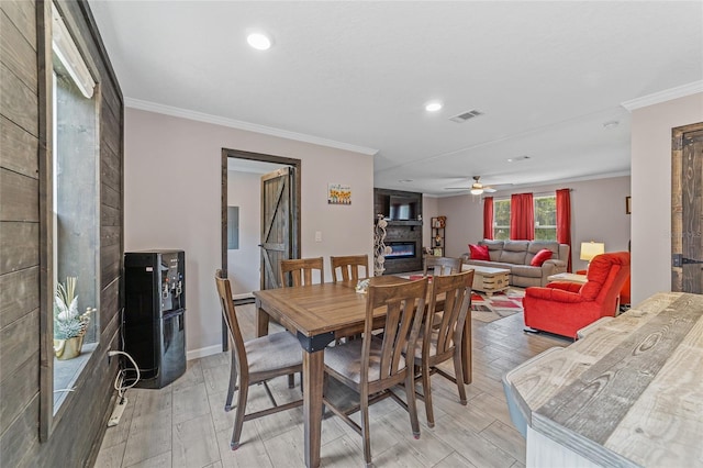 dining space featuring light hardwood / wood-style flooring, a fireplace, ceiling fan, and crown molding