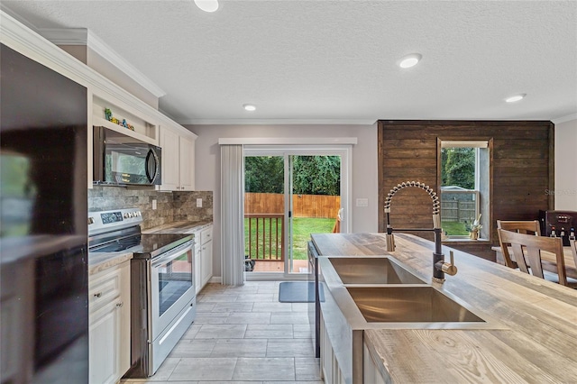 kitchen featuring black fridge, stainless steel electric range oven, a healthy amount of sunlight, and sink