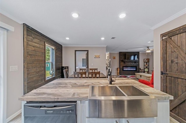 kitchen with sink, ceiling fan, a fireplace, crown molding, and dishwasher