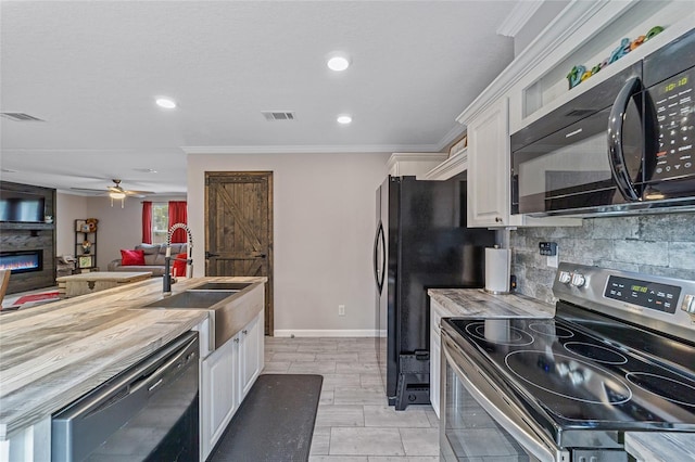 kitchen with white cabinetry, a large fireplace, black appliances, and wooden counters