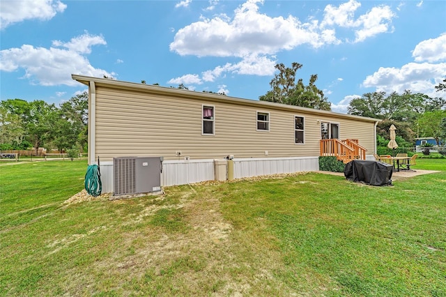 rear view of property with a lawn and central AC