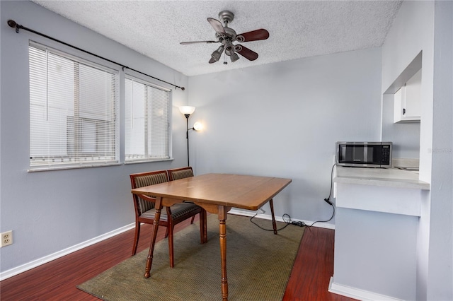 dining space with a textured ceiling, ceiling fan, and dark hardwood / wood-style flooring