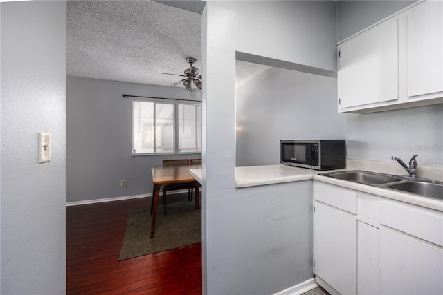 kitchen featuring white cabinets, ceiling fan, a textured ceiling, hardwood / wood-style flooring, and sink