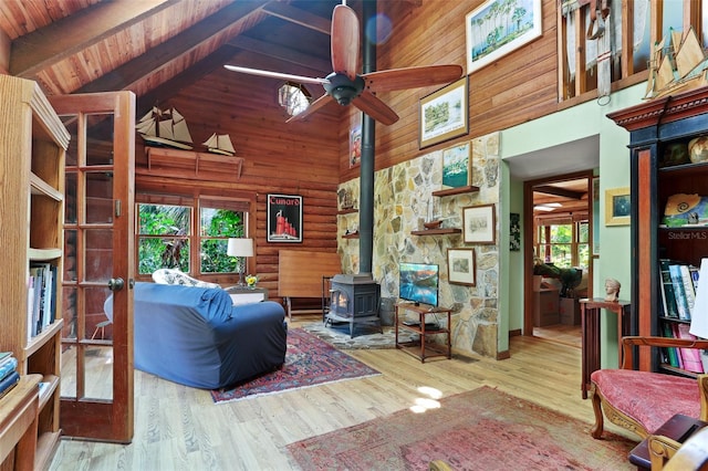 living room with light hardwood / wood-style flooring, wood ceiling, high vaulted ceiling, and a wood stove