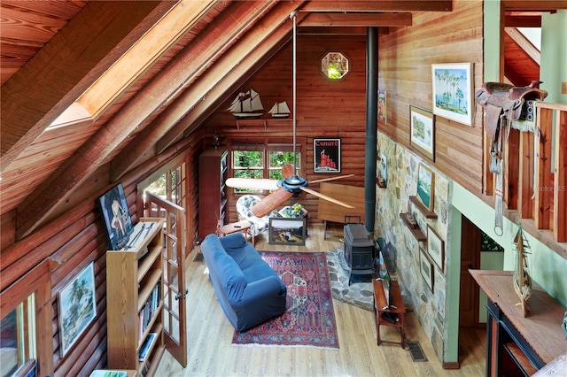 living room with light hardwood / wood-style floors, vaulted ceiling with beams, a wood stove, and wood walls