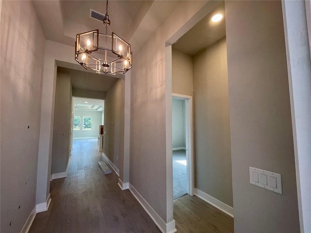 hall featuring a chandelier and dark wood-type flooring