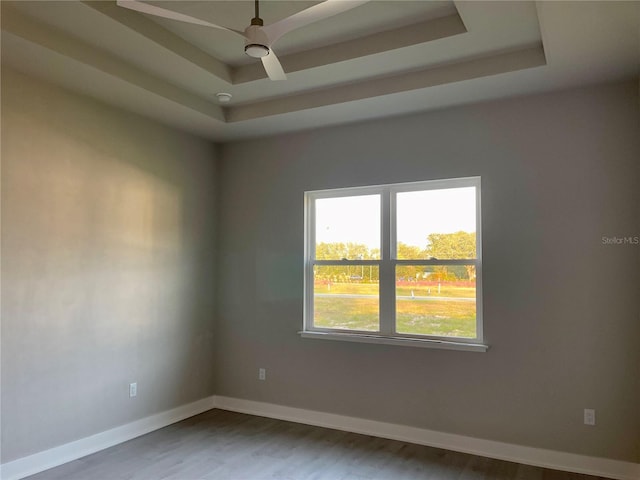 unfurnished room featuring ceiling fan, a tray ceiling, and hardwood / wood-style floors