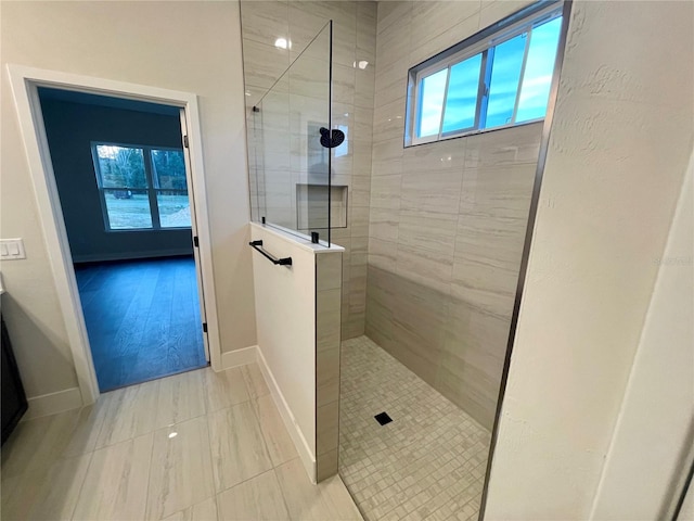 bathroom featuring a tile shower and wood-type flooring