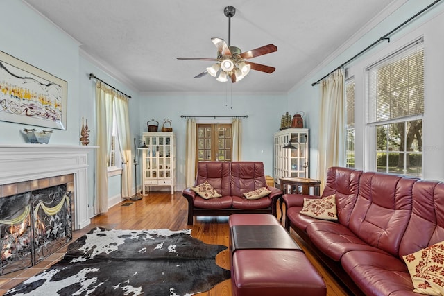 living room with light hardwood / wood-style floors, crown molding, a tile fireplace, and ceiling fan