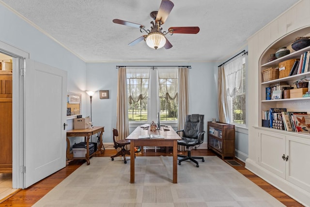 office space with crown molding, a textured ceiling, light wood-type flooring, and ceiling fan