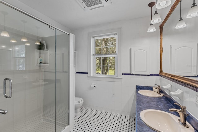 bathroom with a shower with door, toilet, tile walls, and vanity