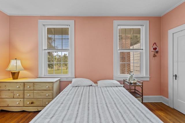 bedroom with multiple windows, ornamental molding, and dark wood-type flooring