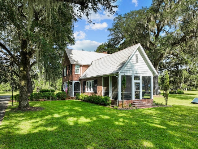 rear view of house featuring a lawn and a sunroom