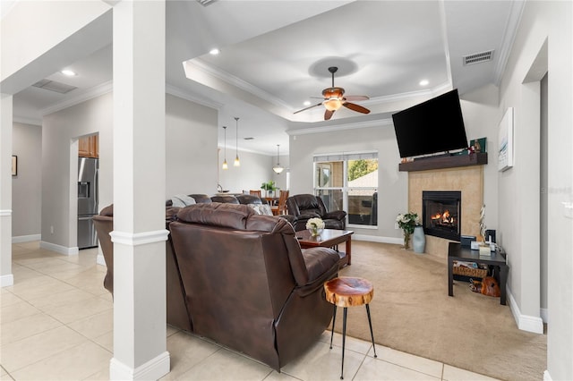 living room with ornamental molding, light carpet, a tile fireplace, and ceiling fan