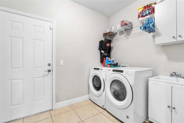 clothes washing area featuring cabinets, light tile patterned flooring, and washing machine and clothes dryer