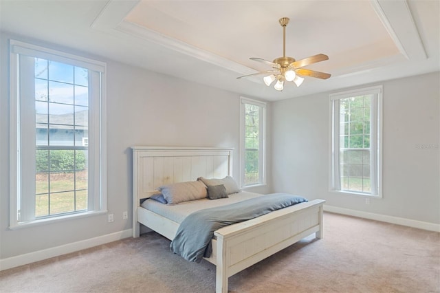 carpeted bedroom with ceiling fan and a tray ceiling