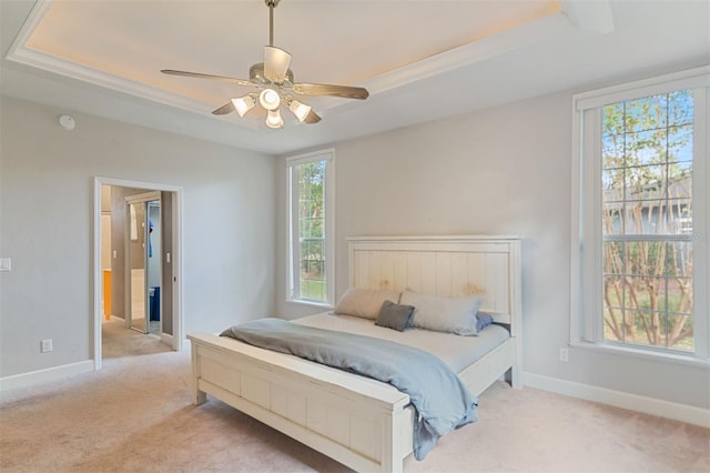 bedroom with multiple windows, ceiling fan, and a tray ceiling