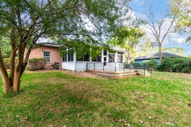 rear view of property with a sunroom, a yard, and a wooden deck