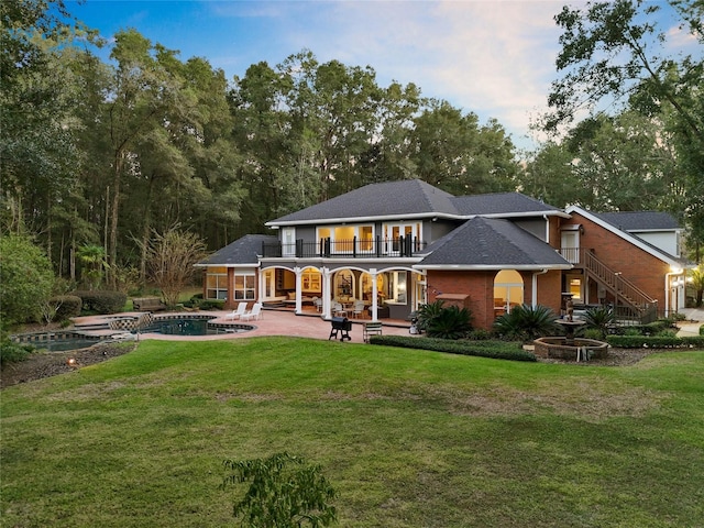 rear view of property with a patio area, a lawn, and a balcony