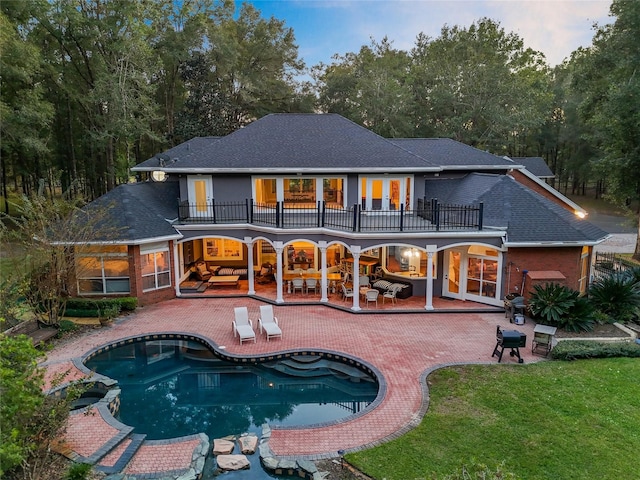 back of property featuring a patio, a yard, and a balcony