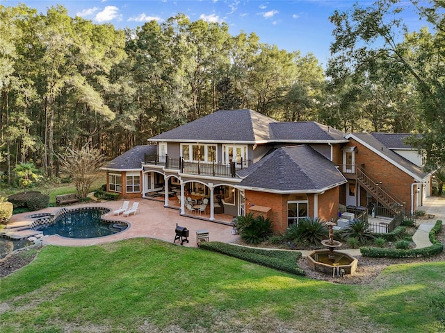 rear view of house with a balcony, a yard, and a patio area