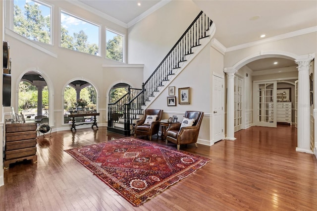 living room featuring a wealth of natural light, hardwood / wood-style floors, a high ceiling, and decorative columns