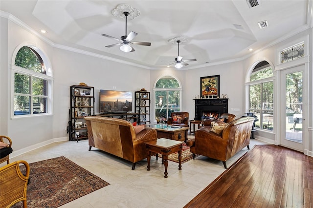 living room with ceiling fan, a healthy amount of sunlight, ornamental molding, and light wood-type flooring