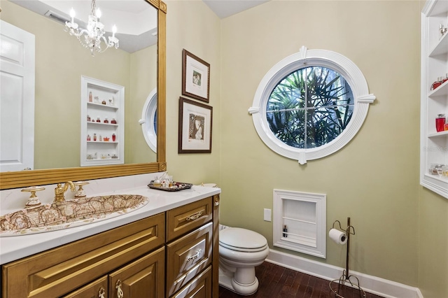 bathroom with toilet, an inviting chandelier, vanity, and wood-type flooring