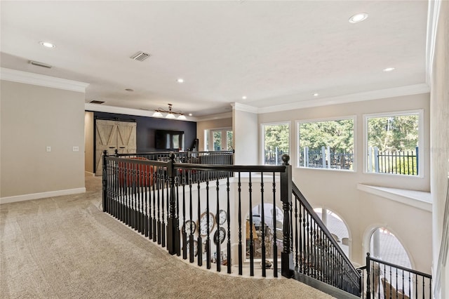 hall featuring light carpet, crown molding, and a barn door