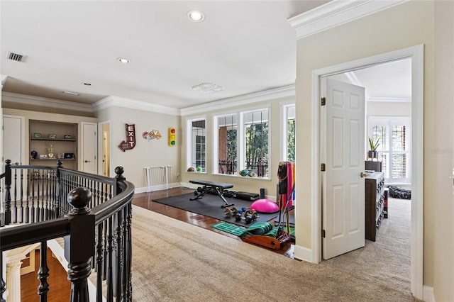 exercise room with a wealth of natural light, hardwood / wood-style floors, and crown molding