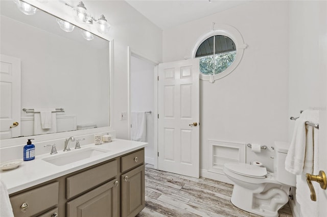 bathroom with toilet, hardwood / wood-style floors, and vanity