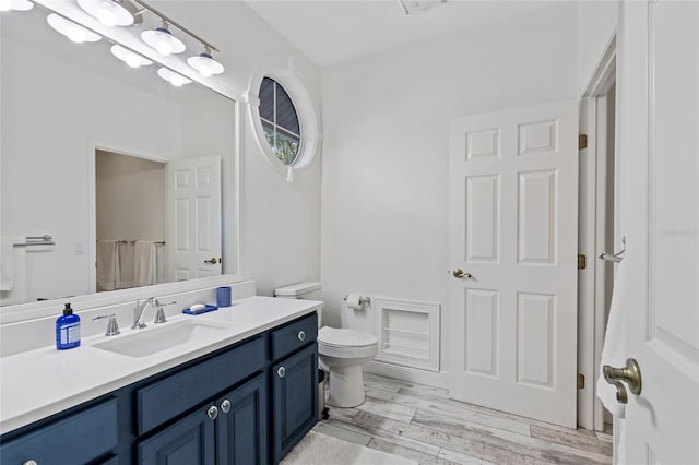 bathroom with toilet, hardwood / wood-style floors, walk in shower, and vanity