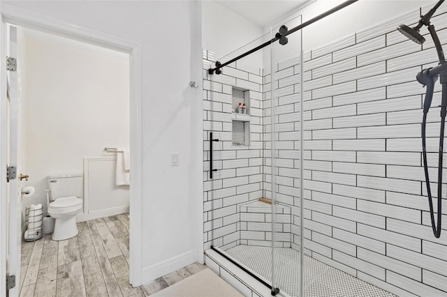 bathroom with hardwood / wood-style floors, toilet, and an enclosed shower