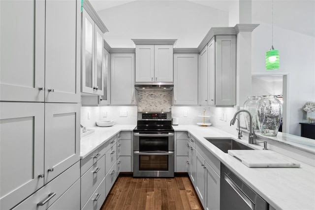 kitchen with sink, stainless steel appliances, lofted ceiling, and hanging light fixtures