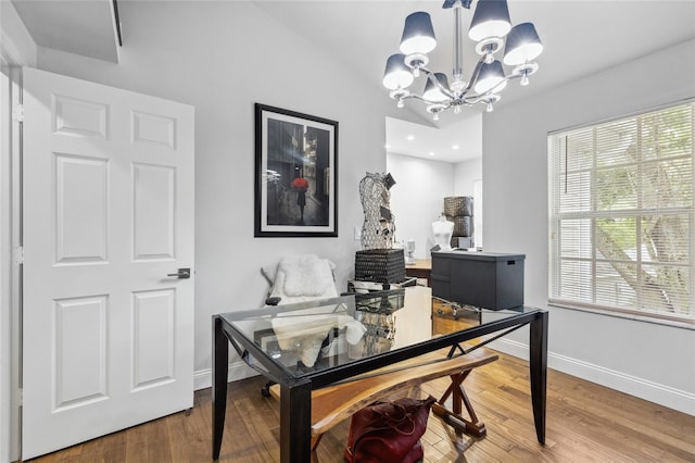 office space with a notable chandelier, hardwood / wood-style floors, and lofted ceiling