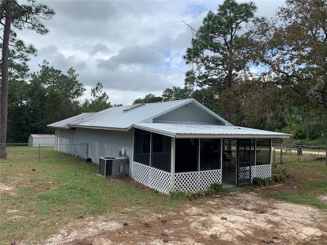 rear view of property with central AC unit and a sunroom