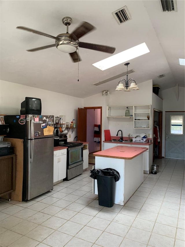 kitchen featuring hanging light fixtures, stainless steel appliances, ceiling fan with notable chandelier, lofted ceiling with skylight, and a center island