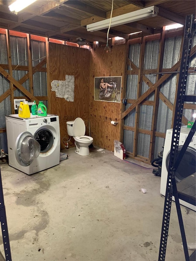 basement featuring wood walls and separate washer and dryer