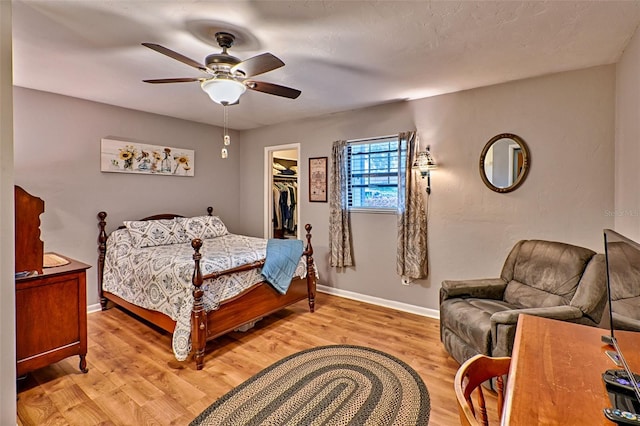 bedroom with a spacious closet, ceiling fan, a closet, and light hardwood / wood-style flooring