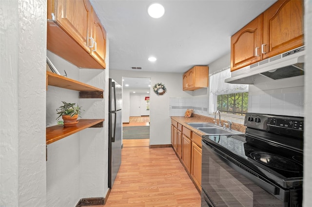 kitchen with decorative backsplash, light hardwood / wood-style flooring, sink, stainless steel fridge, and black range with electric stovetop