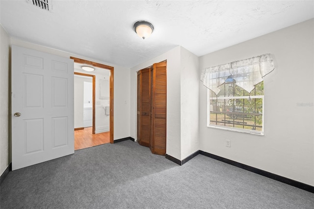 unfurnished bedroom featuring a closet, carpet floors, and a textured ceiling