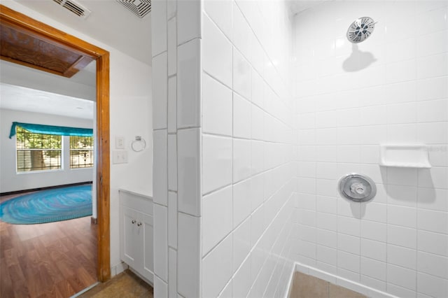 bathroom featuring hardwood / wood-style flooring, a shower, and tile walls