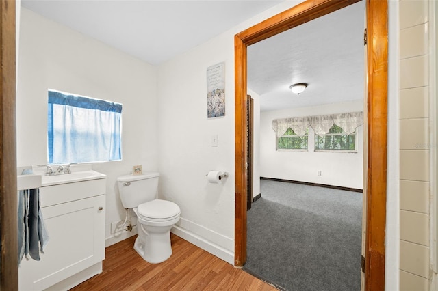 bathroom with toilet, hardwood / wood-style flooring, and vanity