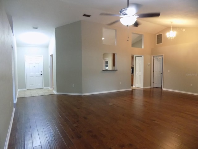 unfurnished living room featuring ceiling fan with notable chandelier, vaulted ceiling, and dark hardwood / wood-style floors