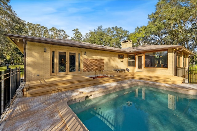 back of property with a fenced in pool, french doors, and a patio area