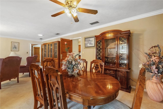 dining room featuring ornamental molding, light carpet, and ceiling fan