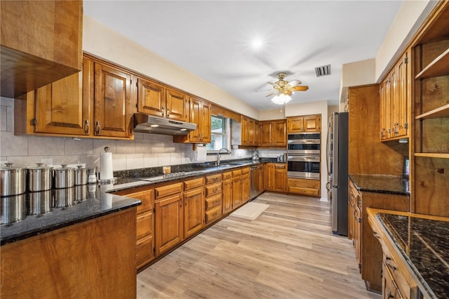 kitchen with tasteful backsplash, appliances with stainless steel finishes, sink, light hardwood / wood-style floors, and ceiling fan