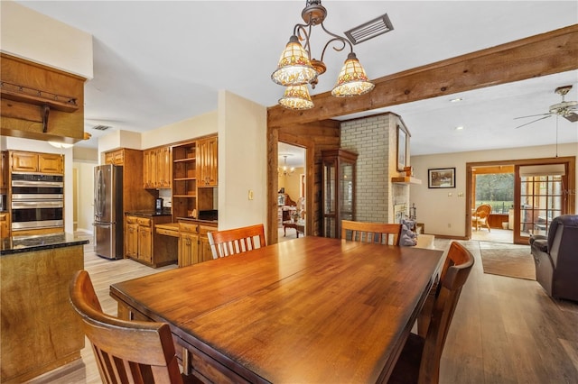 dining area featuring ceiling fan with notable chandelier and light hardwood / wood-style floors