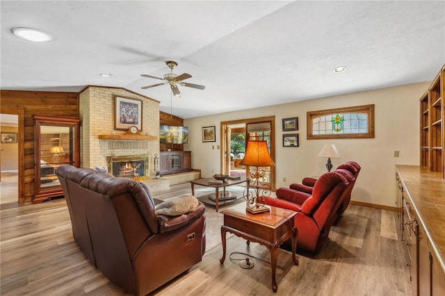 living room featuring lofted ceiling, ceiling fan, light hardwood / wood-style flooring, a fireplace, and wooden walls