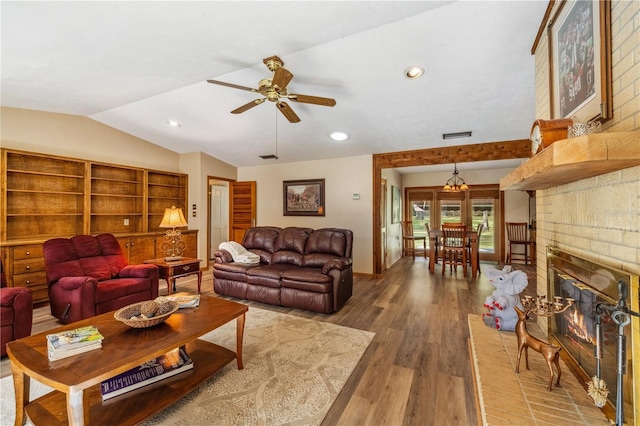 living room featuring lofted ceiling, hardwood / wood-style flooring, a fireplace, and ceiling fan